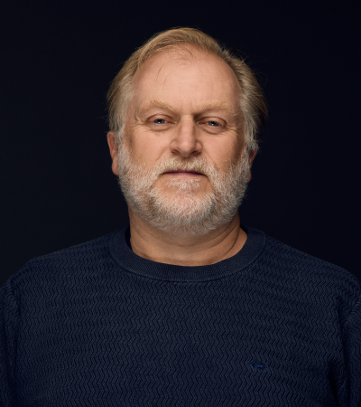 Ben is a middle-aged Caucasian male with short blond hair and grey beard. Ben is wearing a navy jumper and looking at the camera.