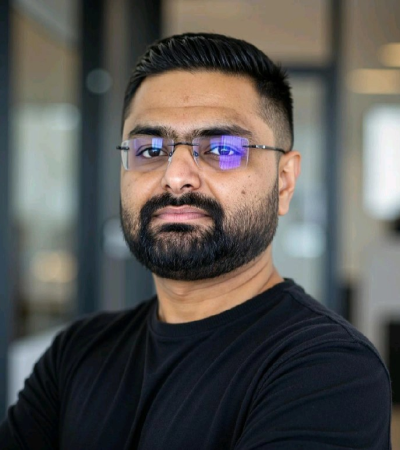 Headshot of Darshit - a man with dark hair and beard, wearing glasses and a black shirt. Darshit is looking at the camera. 