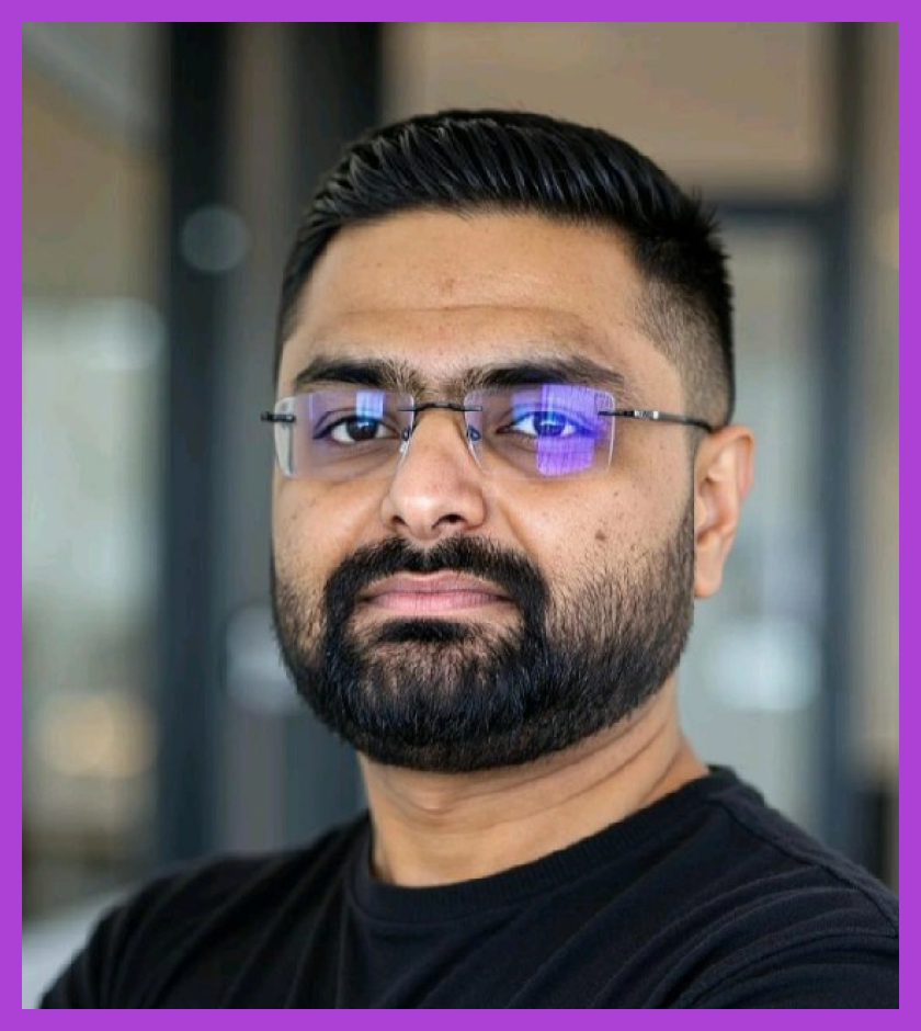 Headshot of Darshit - a man with dark hair and beard, wearing glasses and a black shirt. Darshit is looking at the camera. 