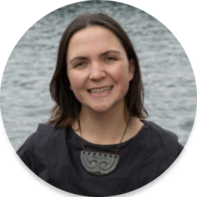 Alyce is part Maori and part Pakeha. She has dark brown eyes and dark hair. She is wearing a black top and pounamu.