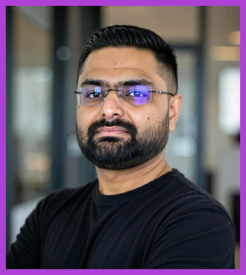 Headshot of Darshit - a man with dark hair and beard, wearing glasses and a black shirt. Darshit is looking at the camera.