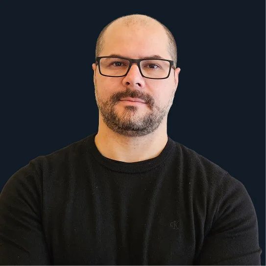 Alt is a middle-aged Brazillian male with light skin and dark hair. Alt is wearing a black tshirt and looking at the camera. 