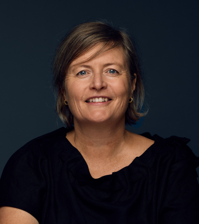 Rachel is a Caucasian woman in her mid-50s with short blonde hair. Rachel is wearing a black blouse and smiling at the camera.