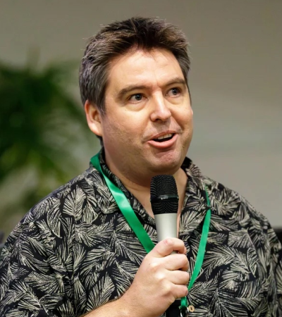 Aaron is a middle-aged white male, with dark brown hair. He is wearing a green floral shirt. 
