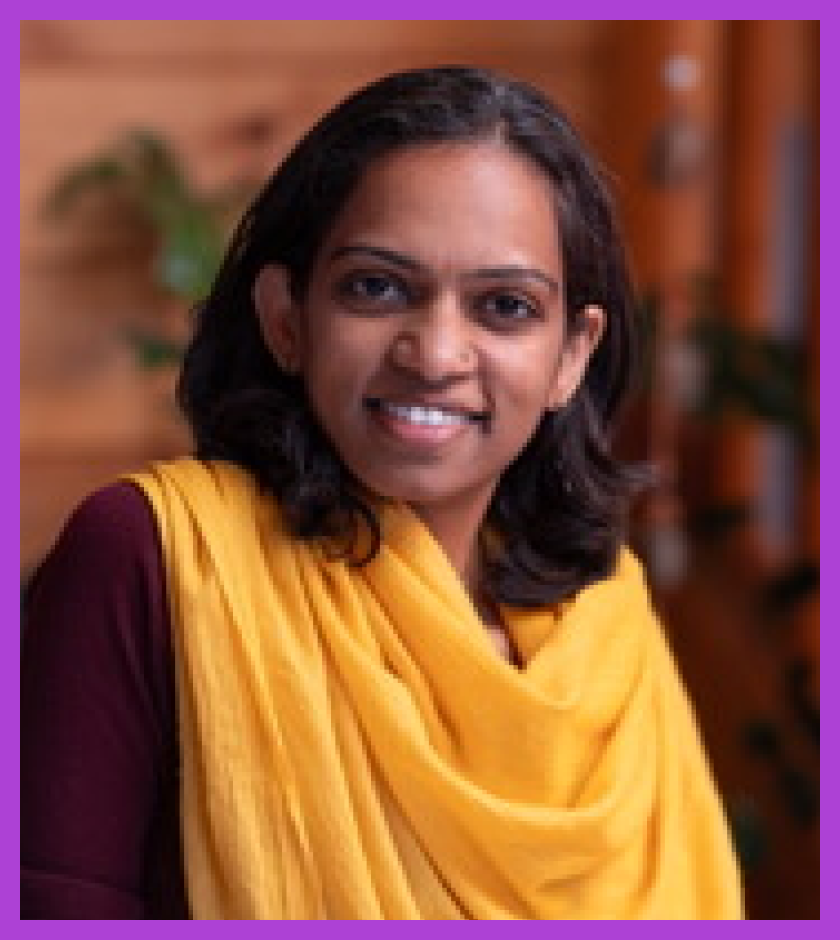 Sahana is a middle aged Indian women with dark hair wearing a maroon top and yellow shawl. She is smiling at the camera.