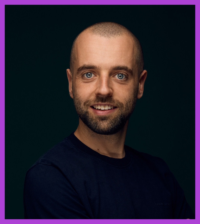 Stuart is a middle aged Caucasian man wearing a blue t-shirt and smiling at the camera.