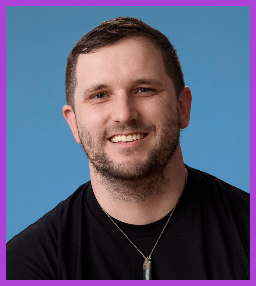 Headshot of Peter - a man in his mid-30’s with short brown hair and stubble wearing a pounamu, and a black shirt with a PrivSec logo.