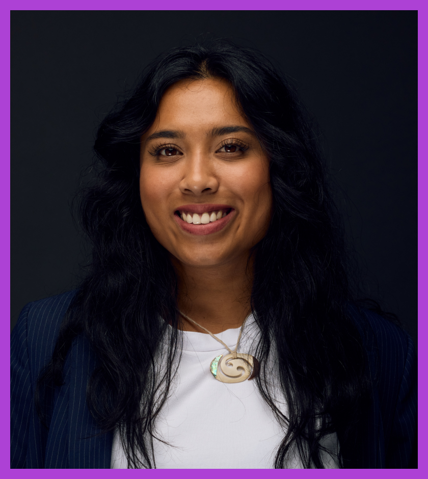 Aleisha is wearing a navy blazer on top of a white tshirt. Aliesha has long dark hair and dark brown eyes. She is smiling at the camera.