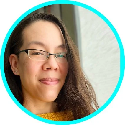 Elise Wei, photo. A dark-haired, light-skinned woman of mixed ethnicity, middle age, and a very high forehead smiles next to a brightly illuminated window. She wears half-rimmed glasses and a yellow, hand-knit jumper.