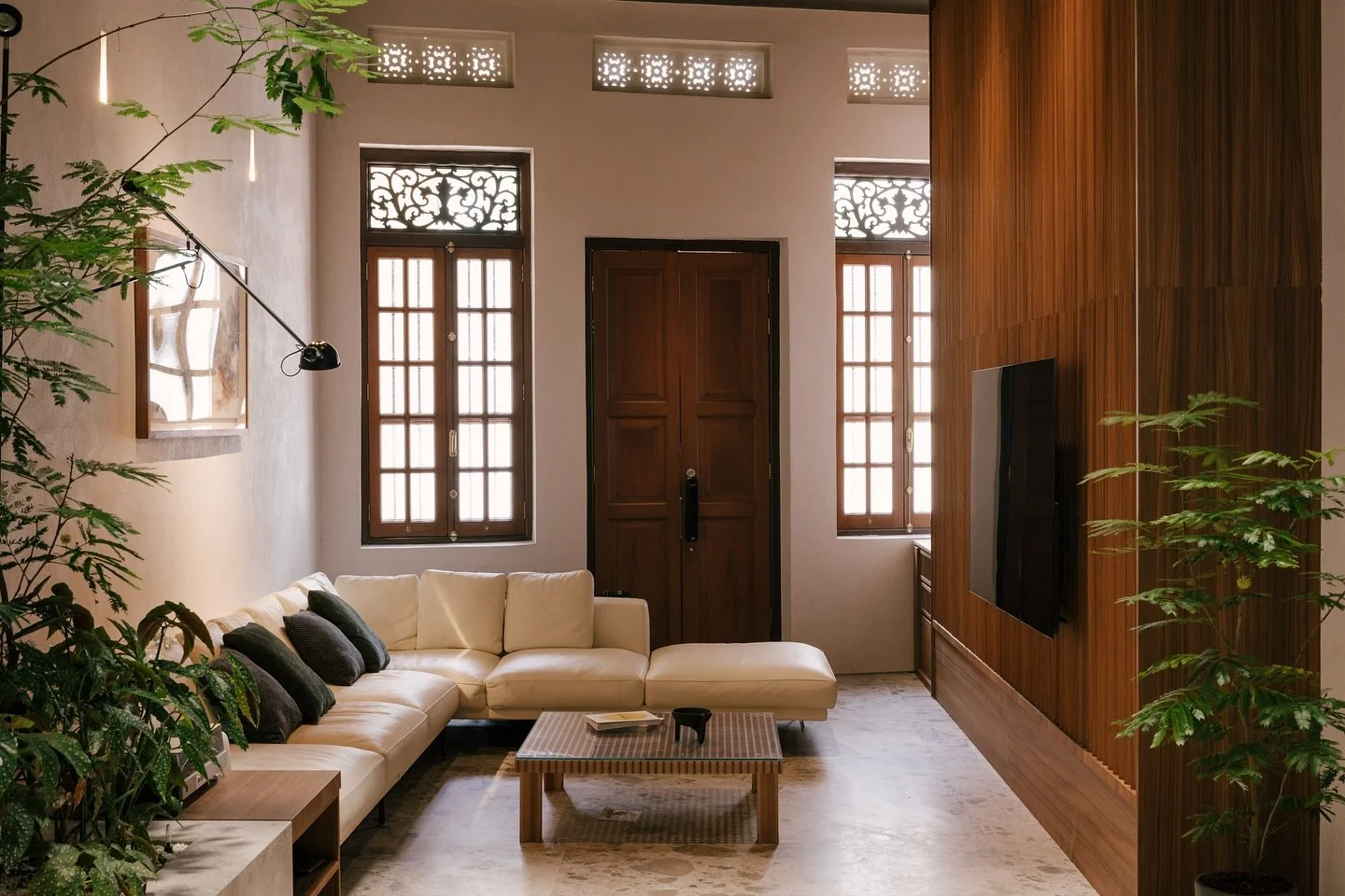 The living room is reimagined as the “forecourt” of the property, forming a threshold at the first airwell between the living and dining space. Framed by warm teak and lush landscape,this transition is marked by material selection –