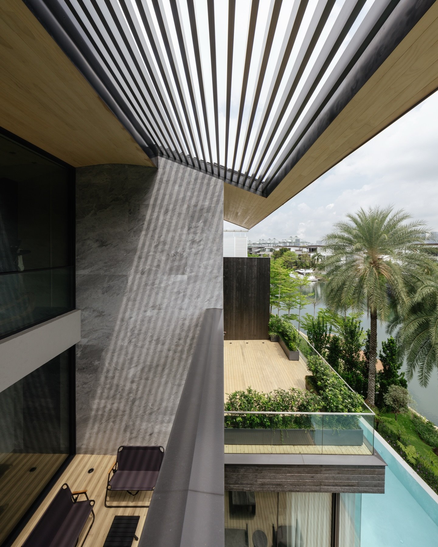 The tonal language of the exterior establishes the foundation for the interior spaces. Inside, the house adopts a restrained and largely monochromatic palette composed of dark oak and champaca, pale grigio olivo mineral limestone and muted blue st bl