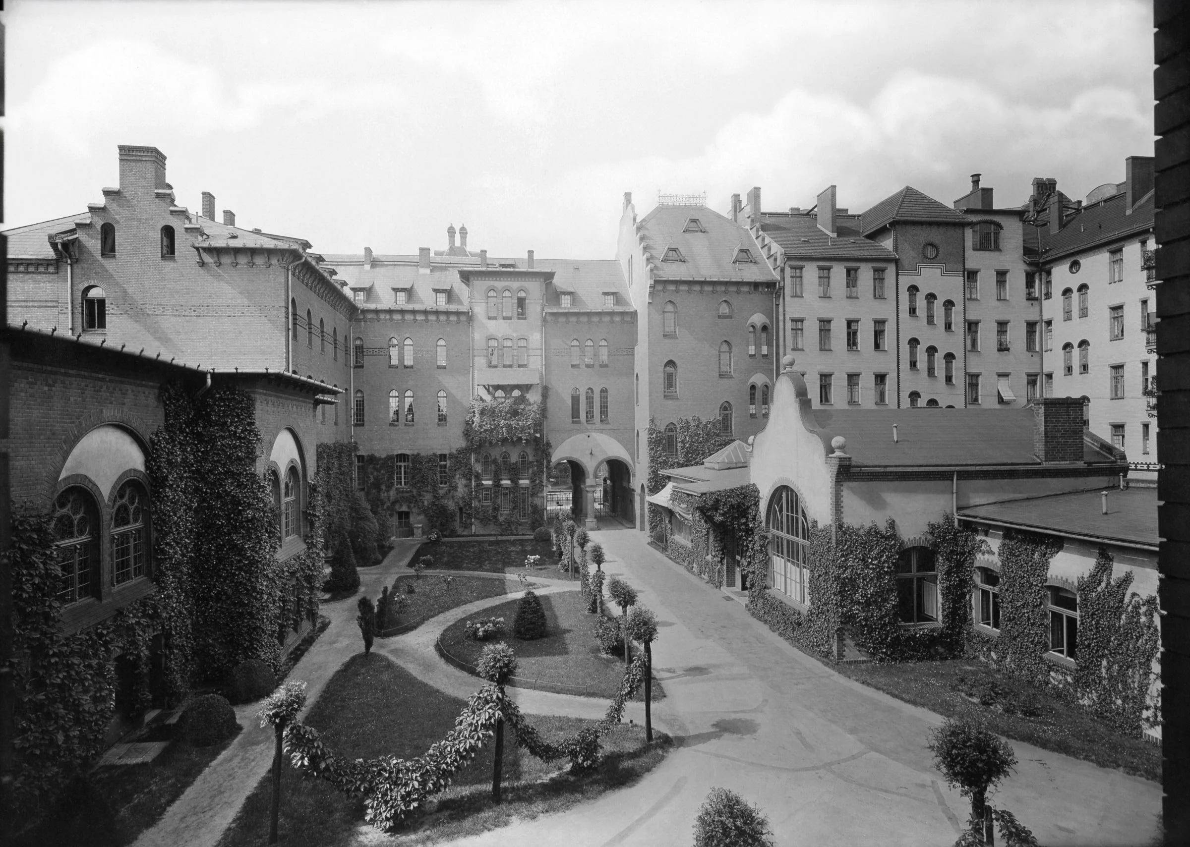 Hof des Paul Gerhardt Stifts um 1910. Links im Anschnitt die Fassade des großen Festsaals, rechts im Vordergrund die Rettungswache mit Poliklinik für die ambulante Versorgung.