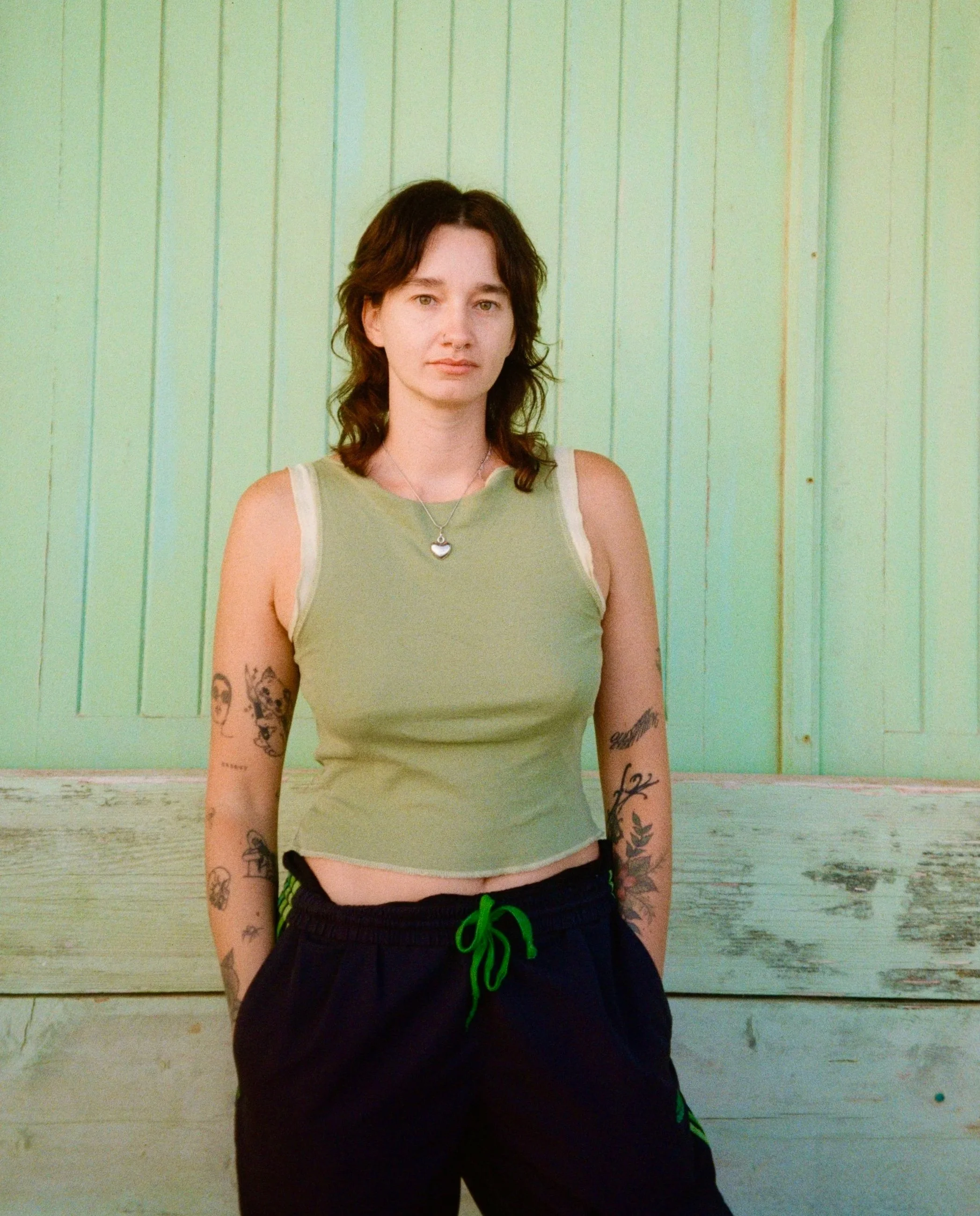 elise (a white girl with brown hair) stands stoney-faced against a pale green backdrop, exhibiting her renowned humour and light-heartedness.
