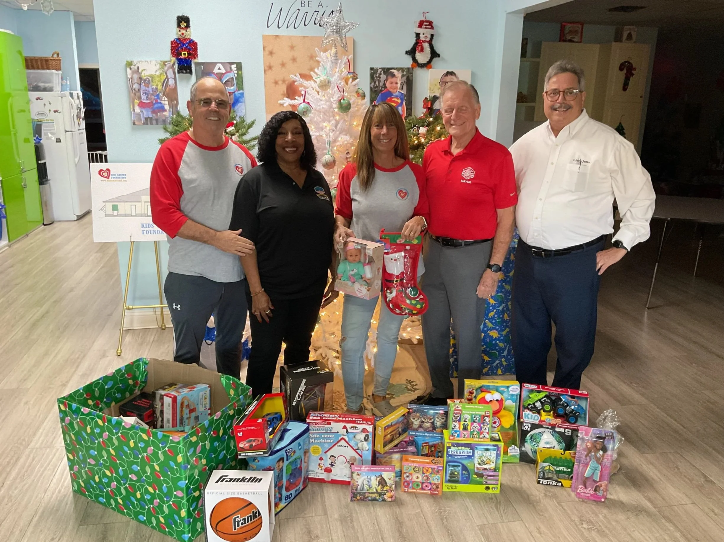 Group of five women and one young girl, with the girl sitting on a stool, in front of a cityscape background.