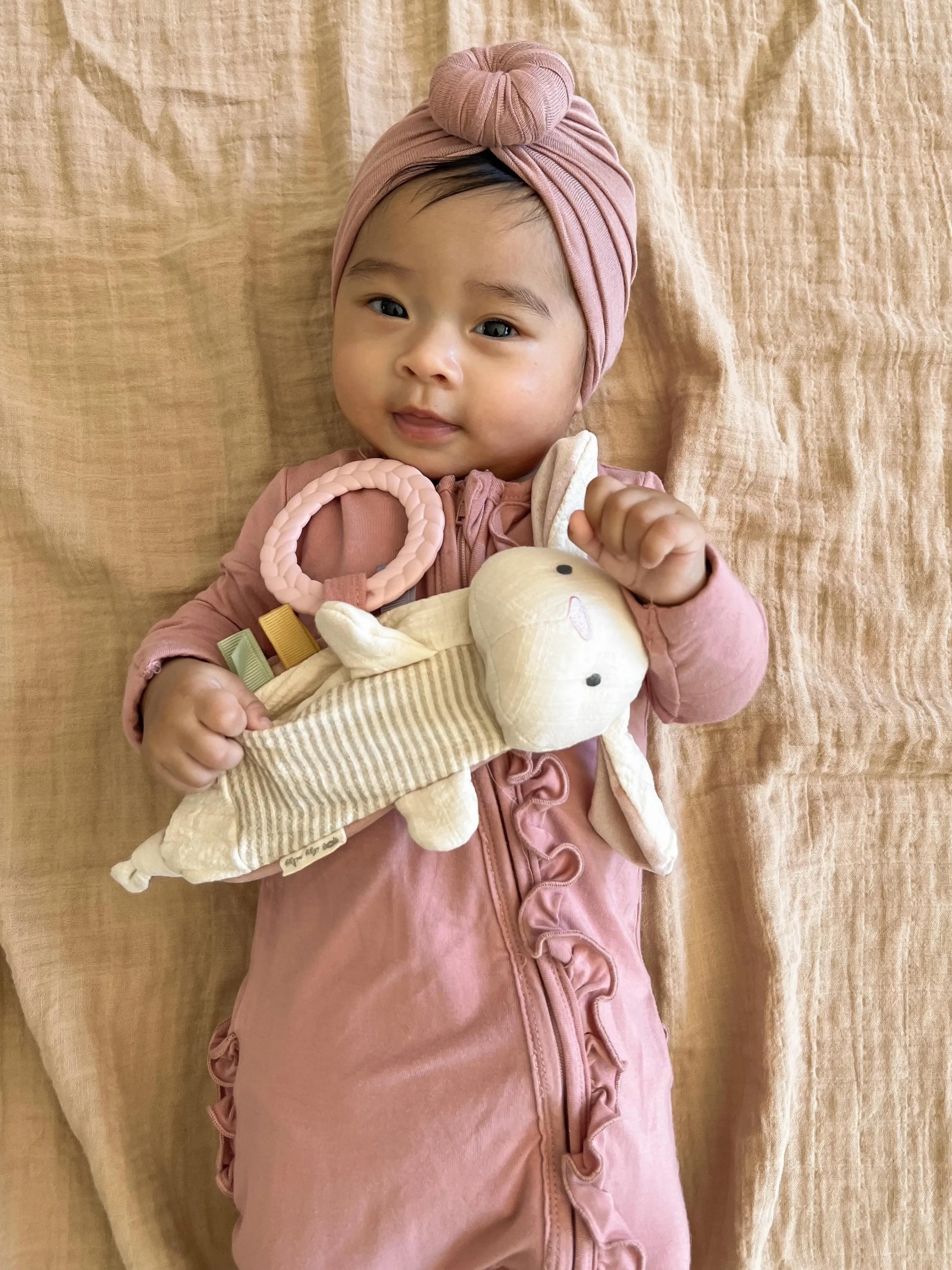 Little girl in pink outfit holding the bitsy crinkle bunny.
