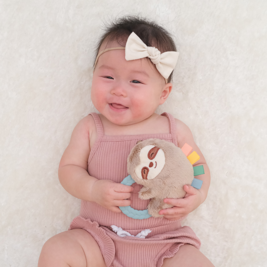 Sweet baby girl playing with the Ritzy Sloth Rattle Pal.