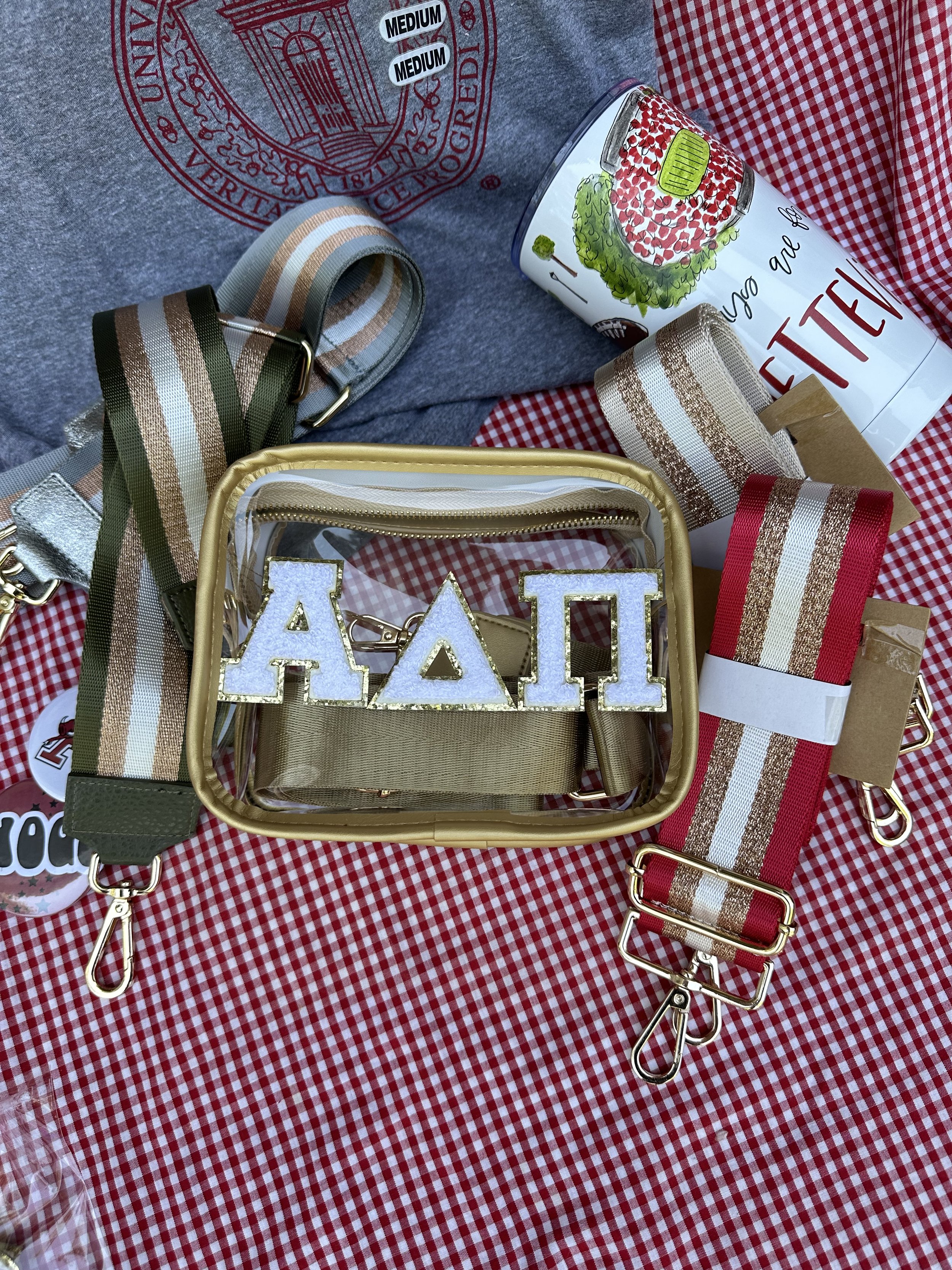 Clear game day handbag with a red, gold, and white striped strap, and white chenille ADPi letters on the front.