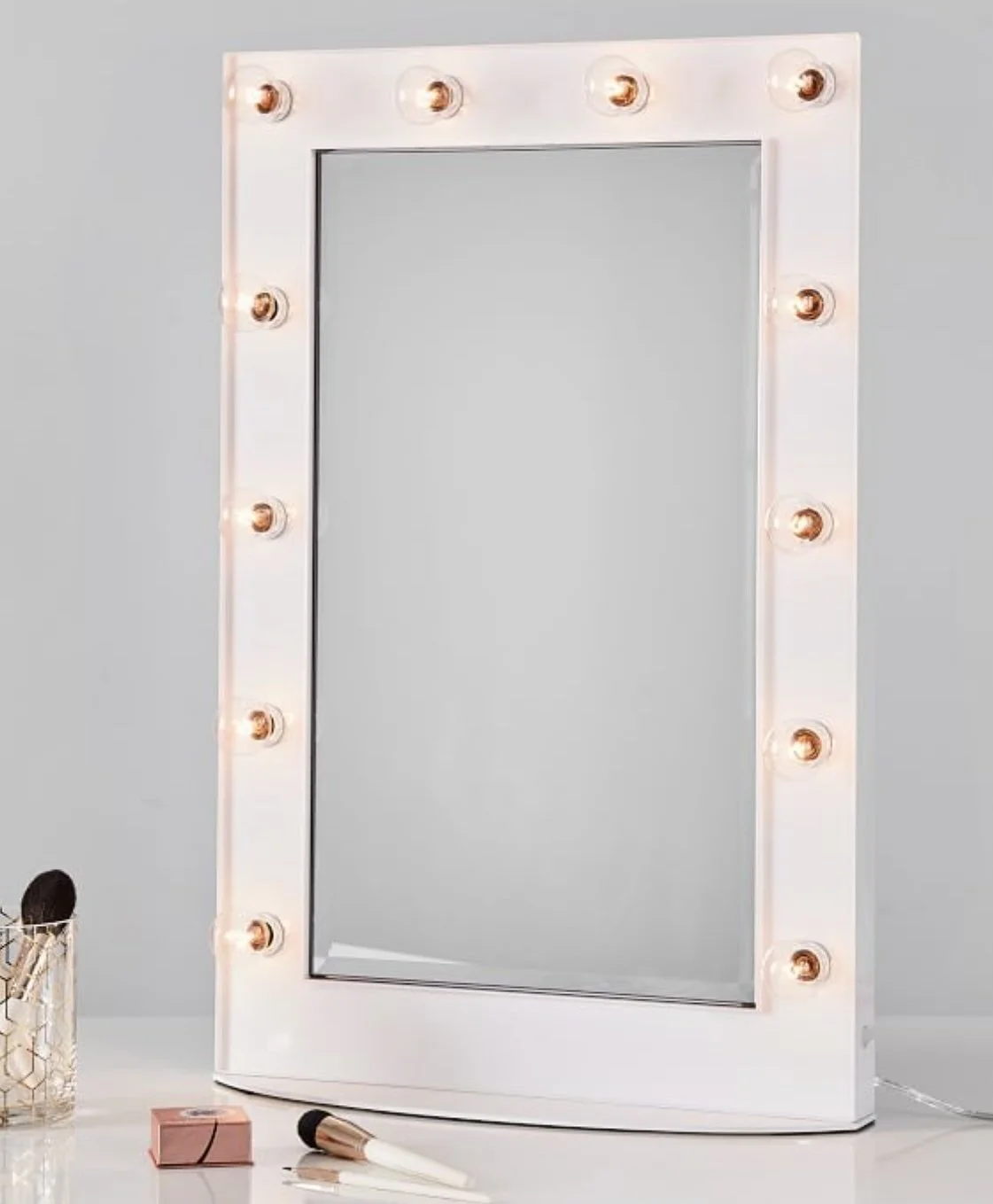 Pottery Barn pale pink mirror for tabletop use, with light bulbs all around.