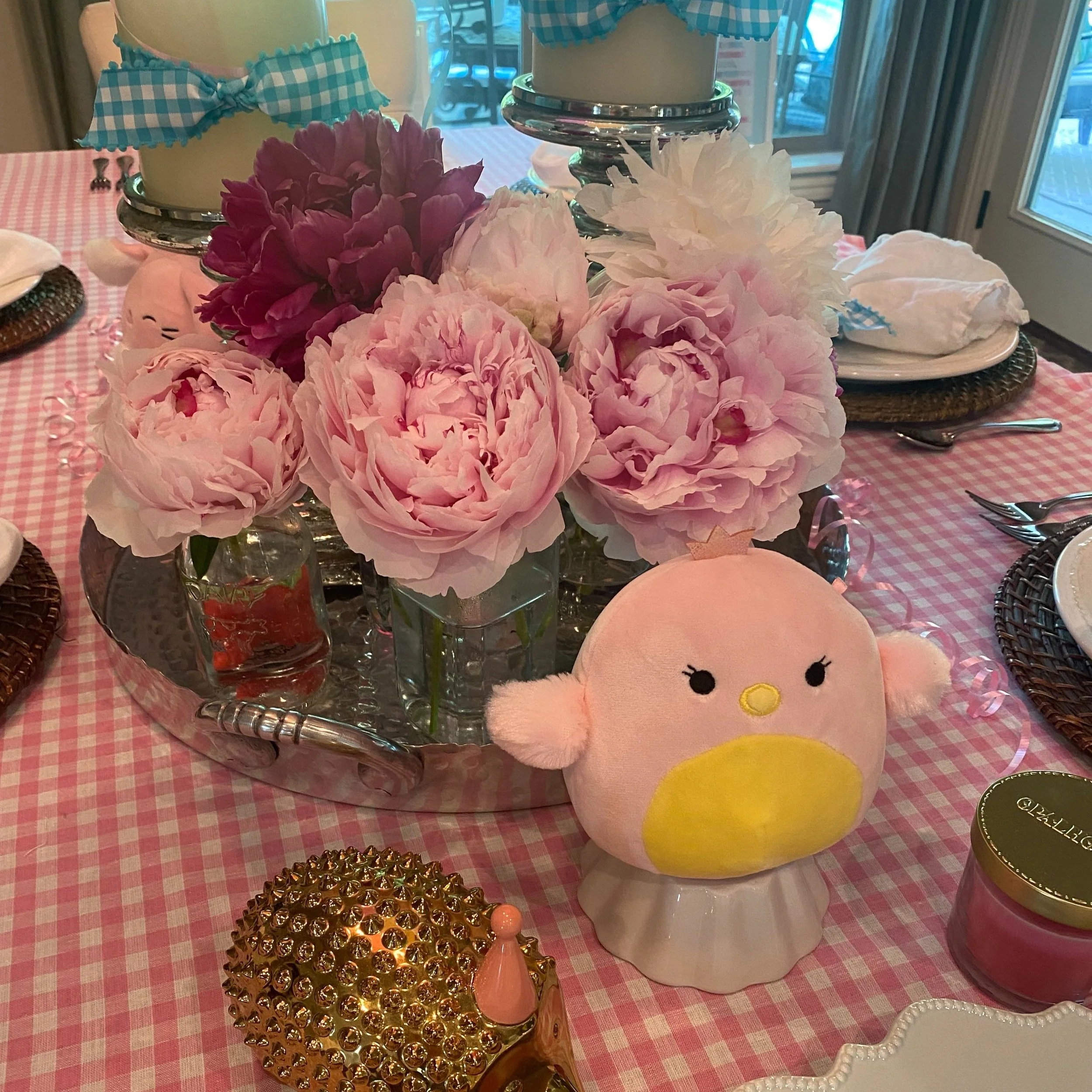Candles, fresh peonies, and table set for dinner.
