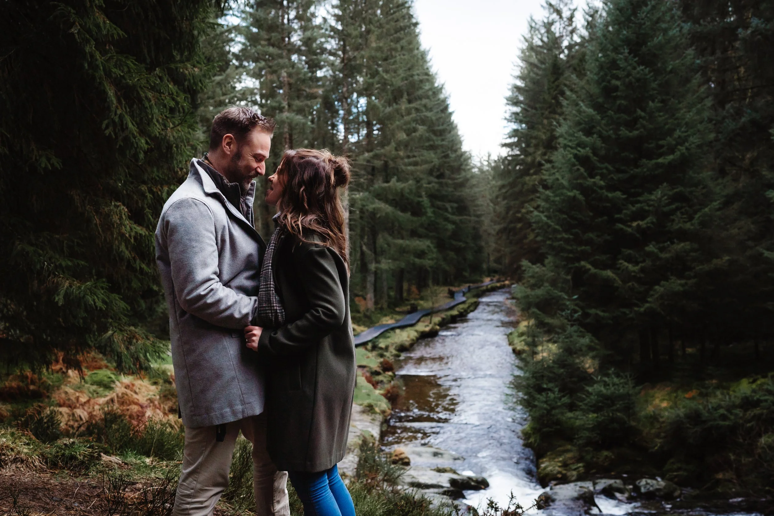 couple embracing at Hafren Forest, the boardwalk and river Severn in the background