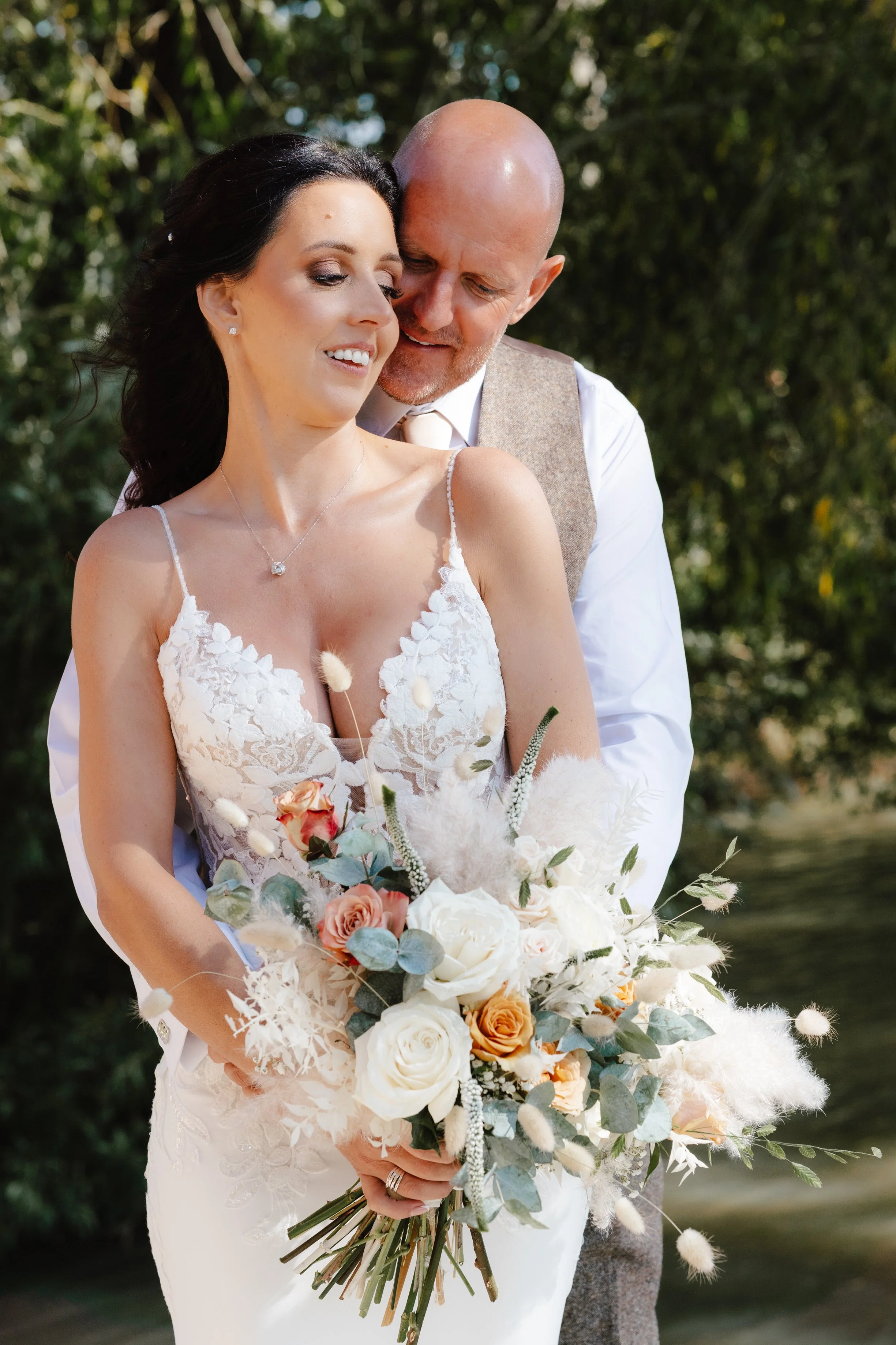 intimate portrait of bride holding bouquet with groom holding her from behind at Garthmyl Hall