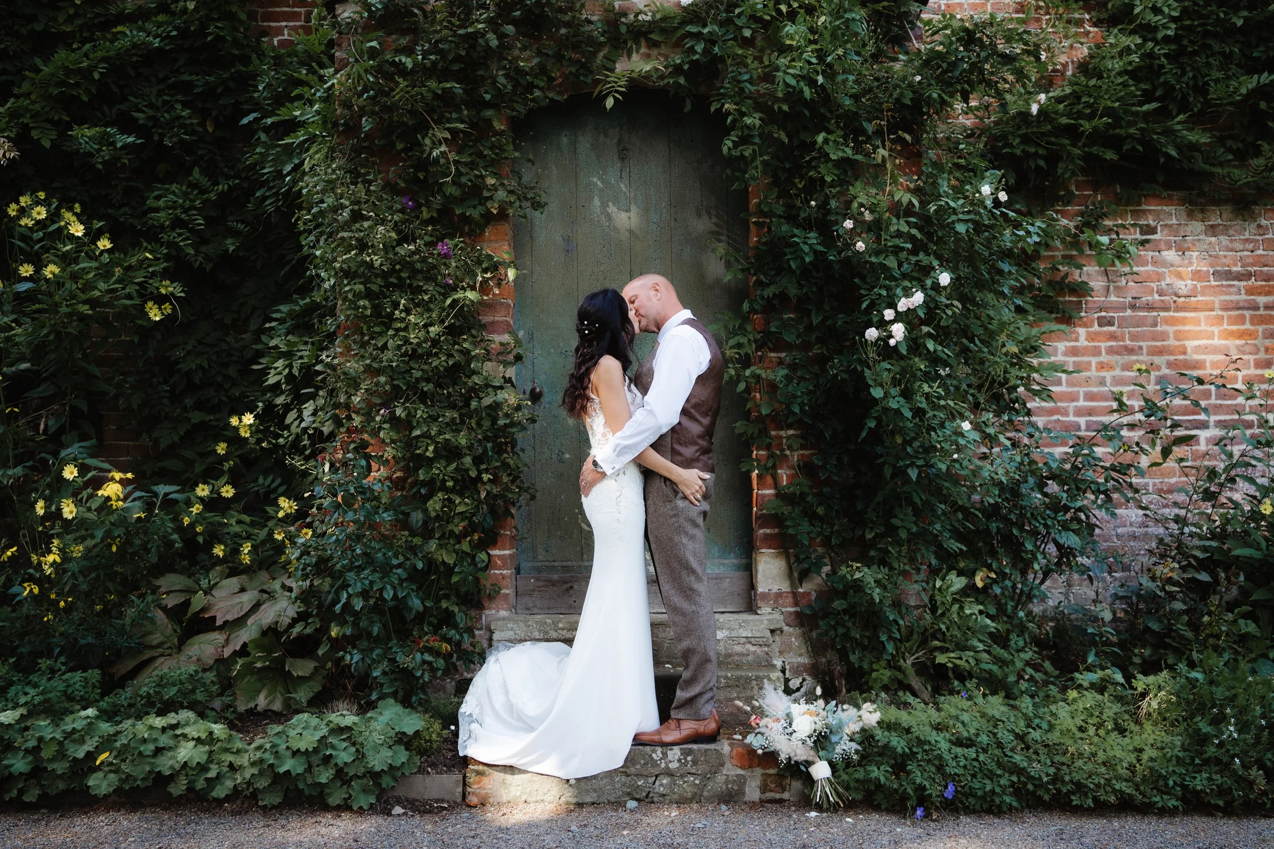 a Garthmyl Hall wedding showing portrait of bride & groom embraced in a kiss at the door to the walled garden