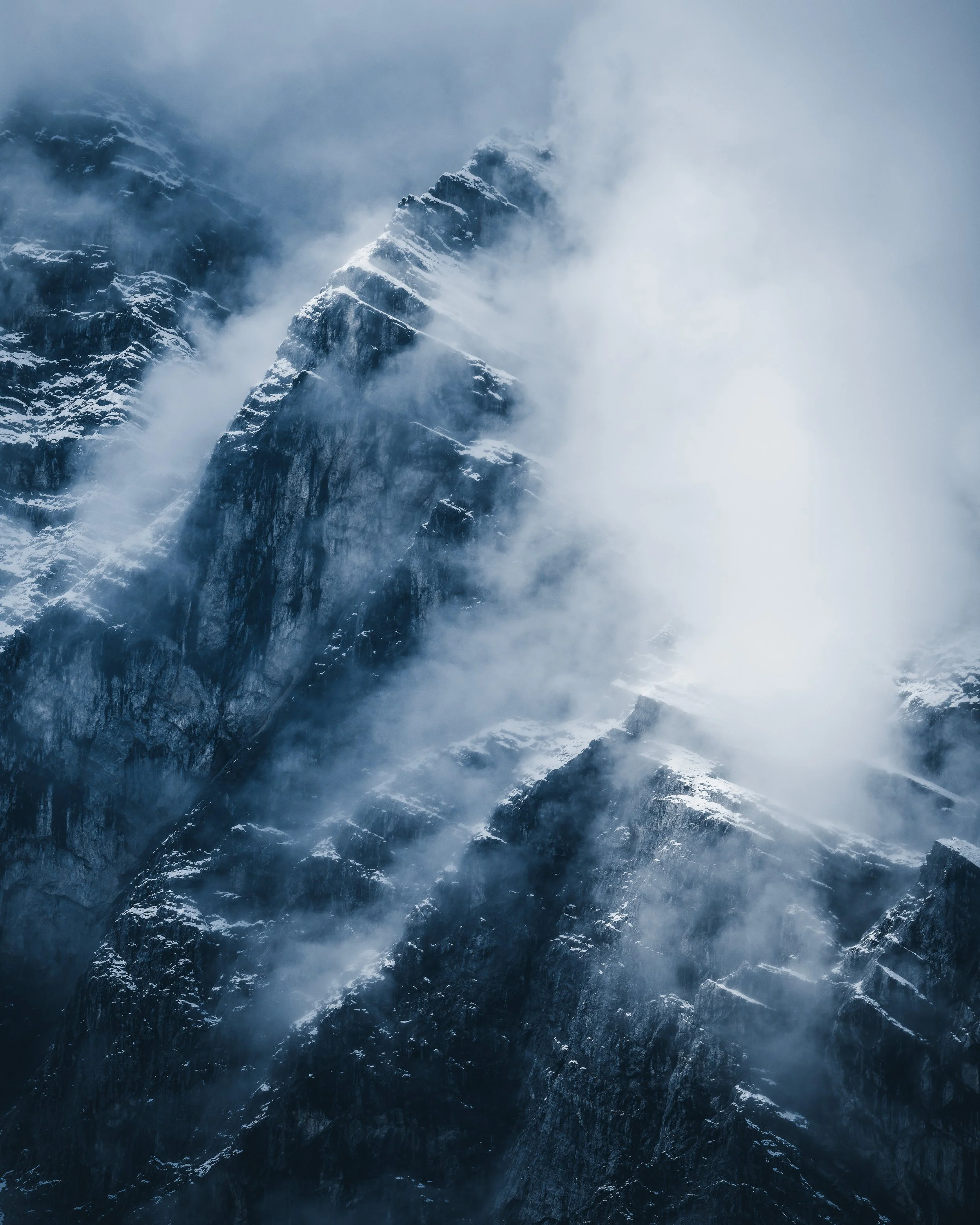 Snowy mountain peaks shrouded in fog and clouds.