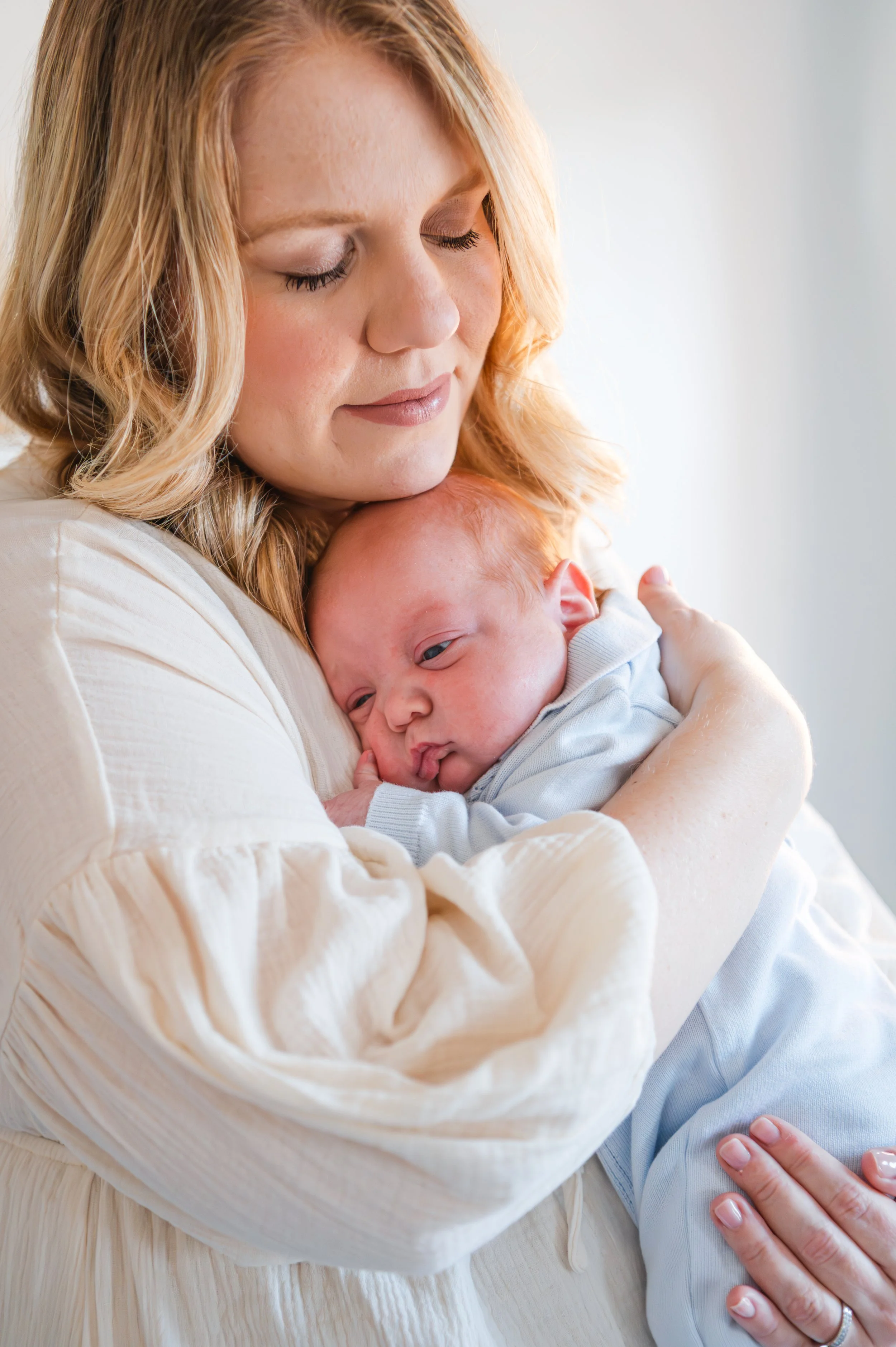 A woman holding a baby close in her arms, with her eyes closed and a gentle expression.