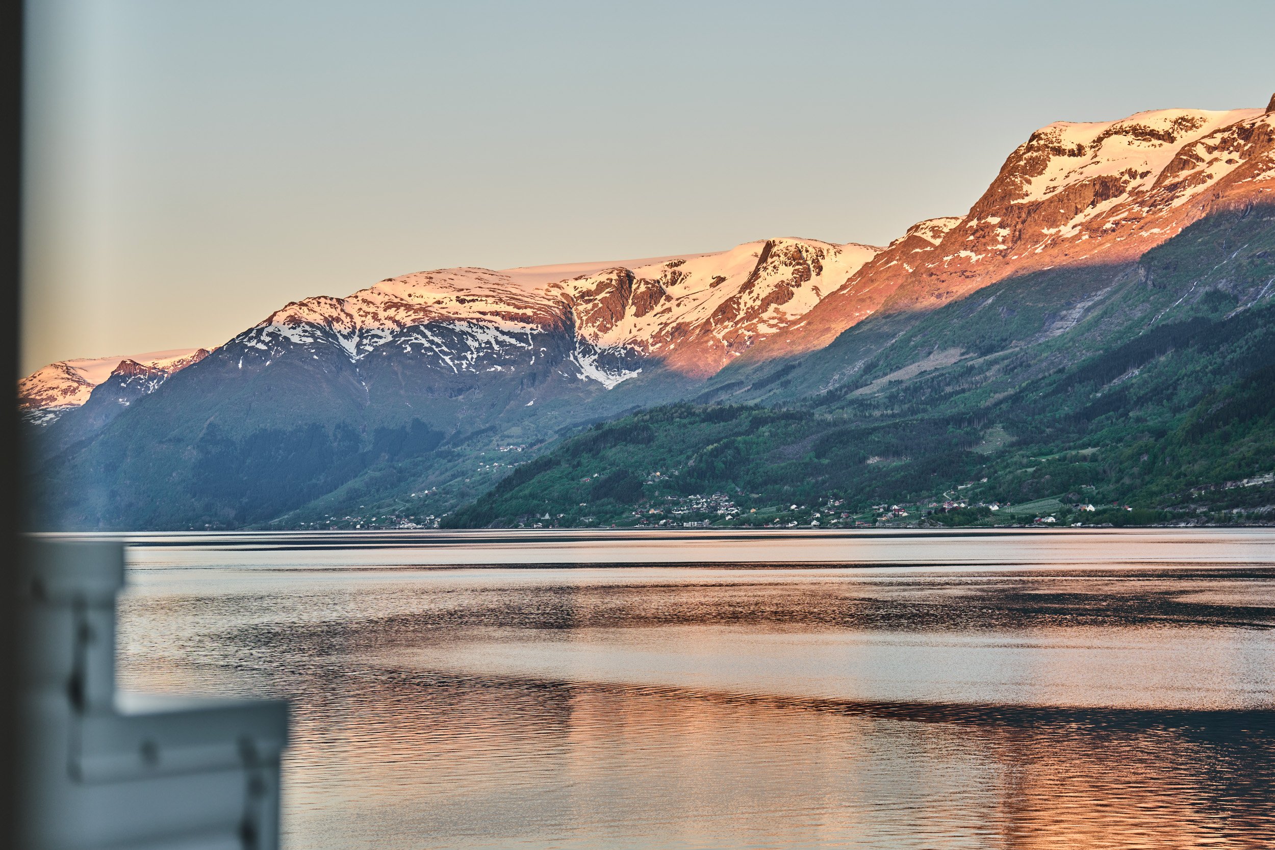 Snow-capped mountains over a calm body of water during sunset