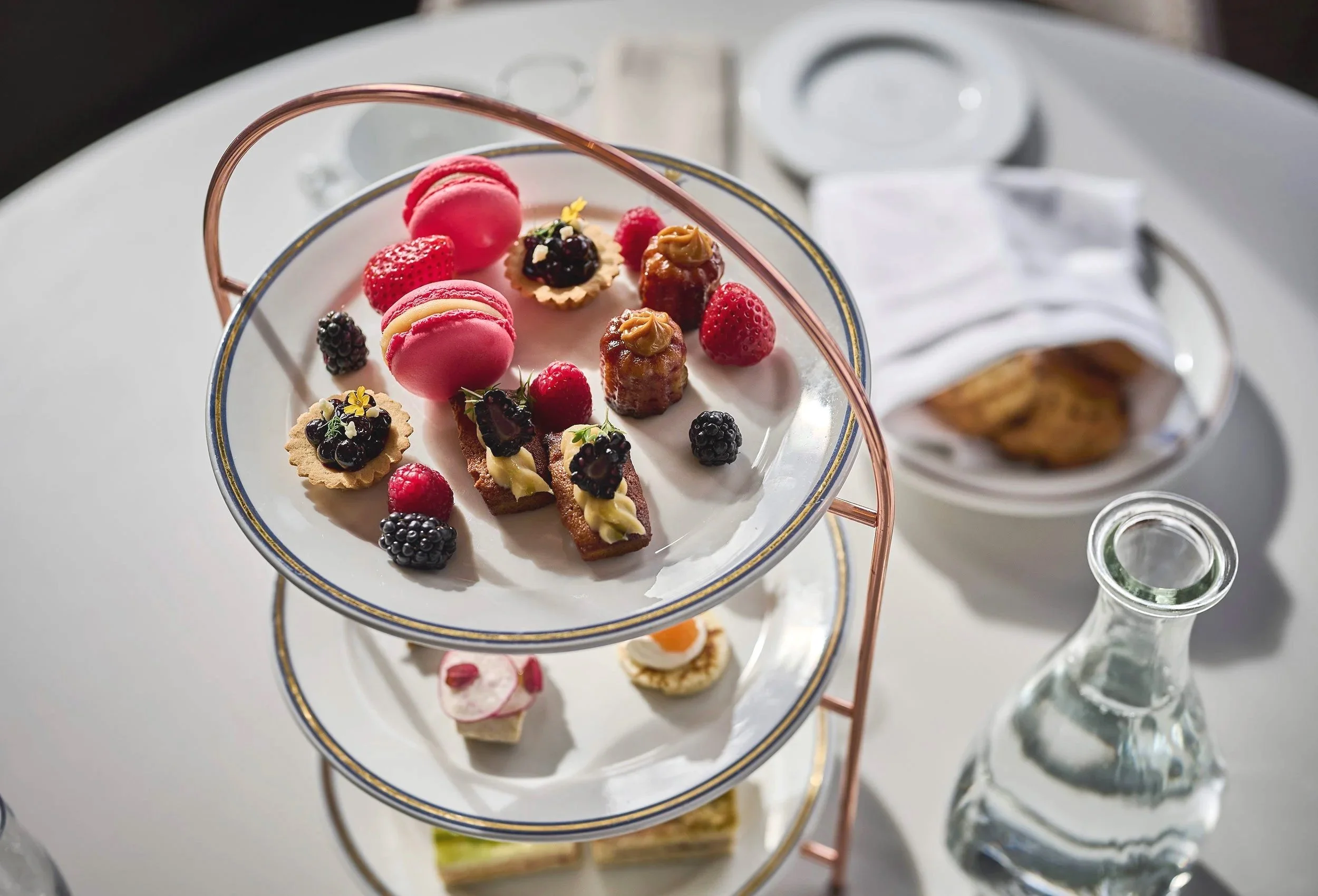 Appealing multi-tiered cake plate with macaroons, fresh berries and cookies