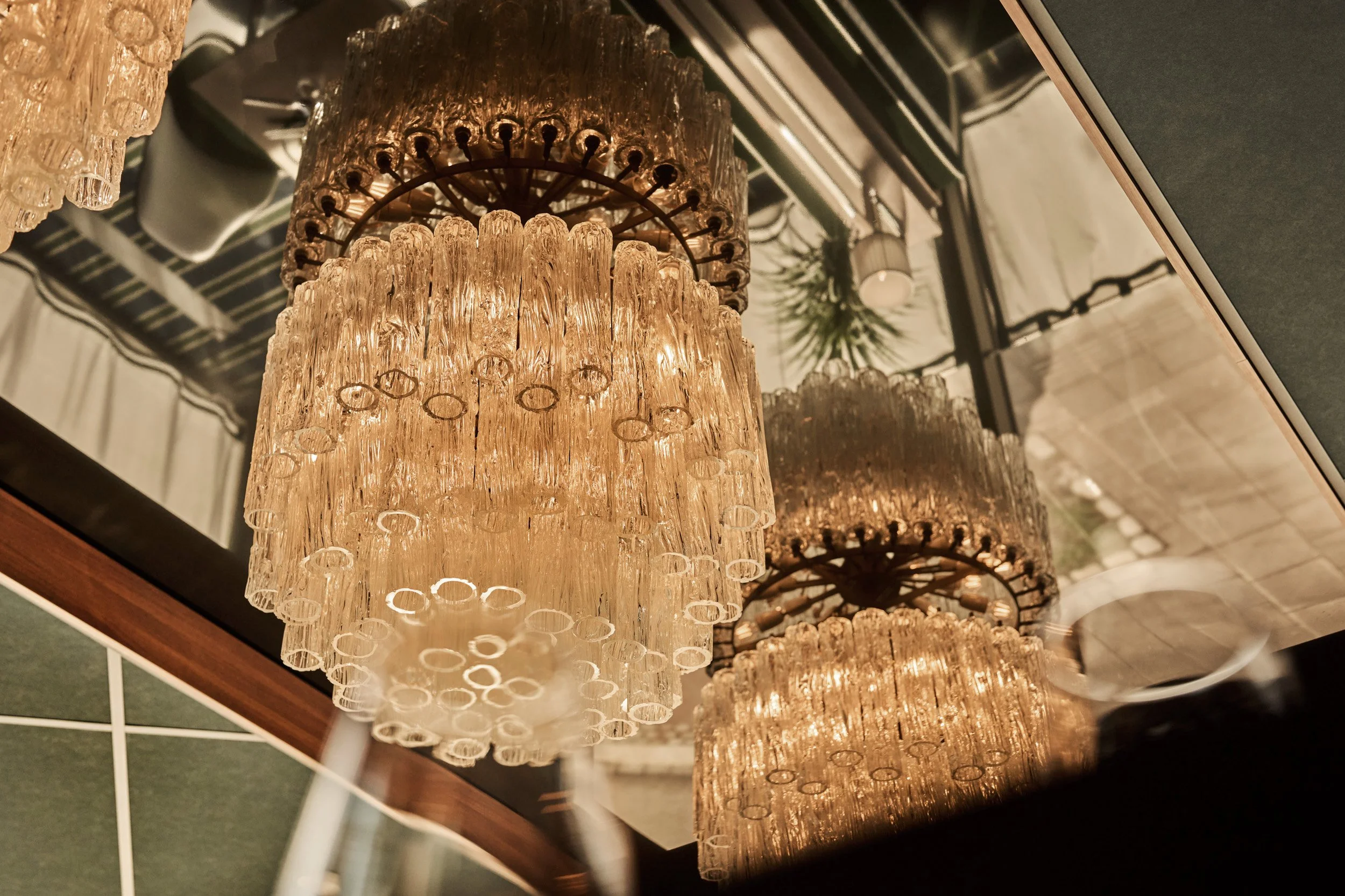 Close-up of elegant crystal chandeliers hanging from a ceiling in a stylish interior space.