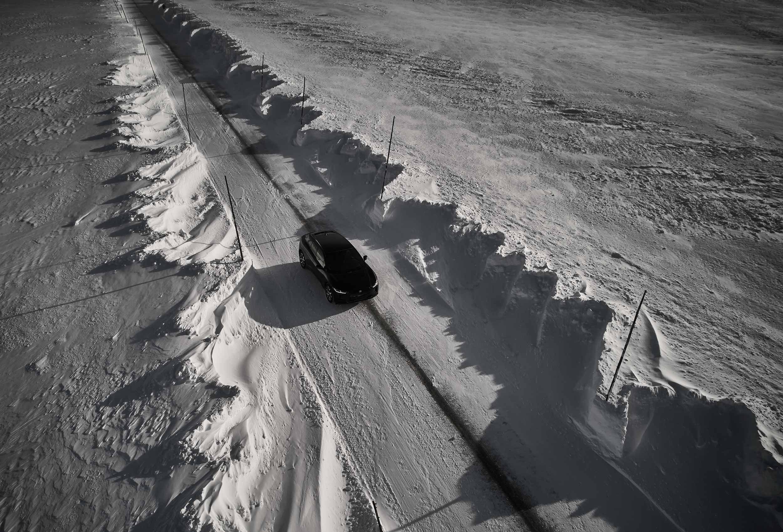 Jaguar I-PACE Land Rover in snow-covered landscape on road. Car photography and drone video in Norway.