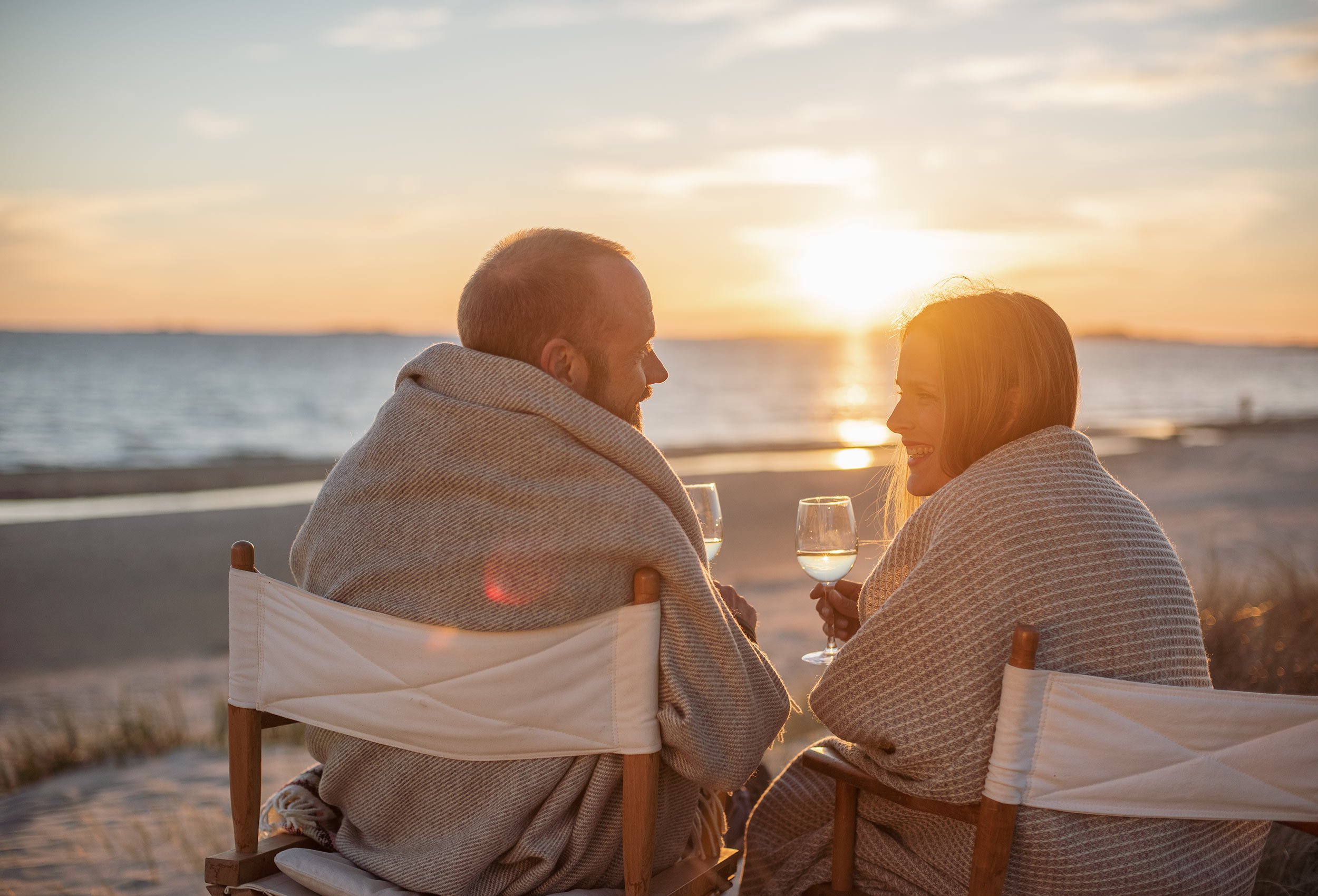 Close-up of romantic couple sitting on folding chairs in the sunset at Sola beach