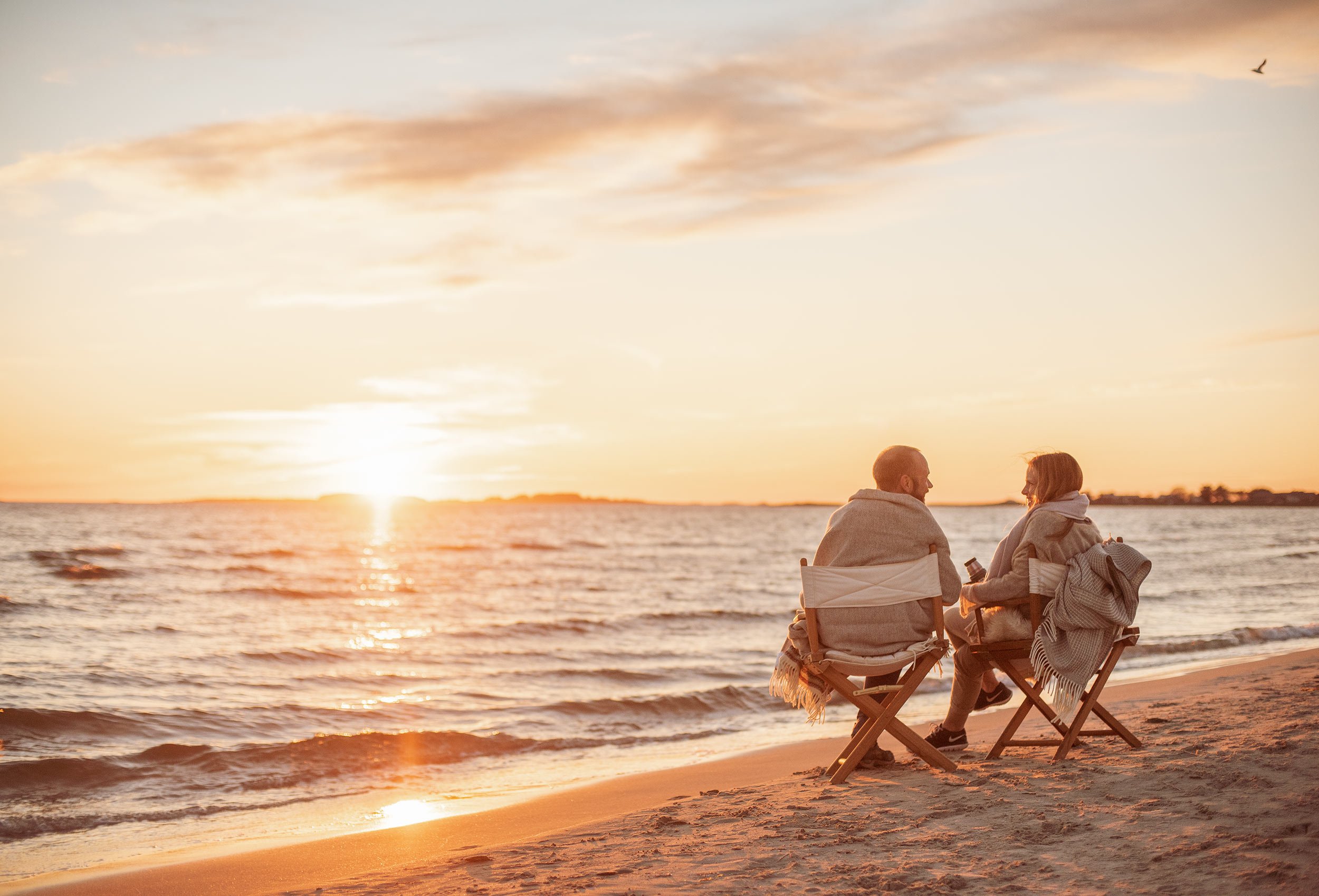 Romantic couple sitting on folding chairs in the sunset at Sola beach