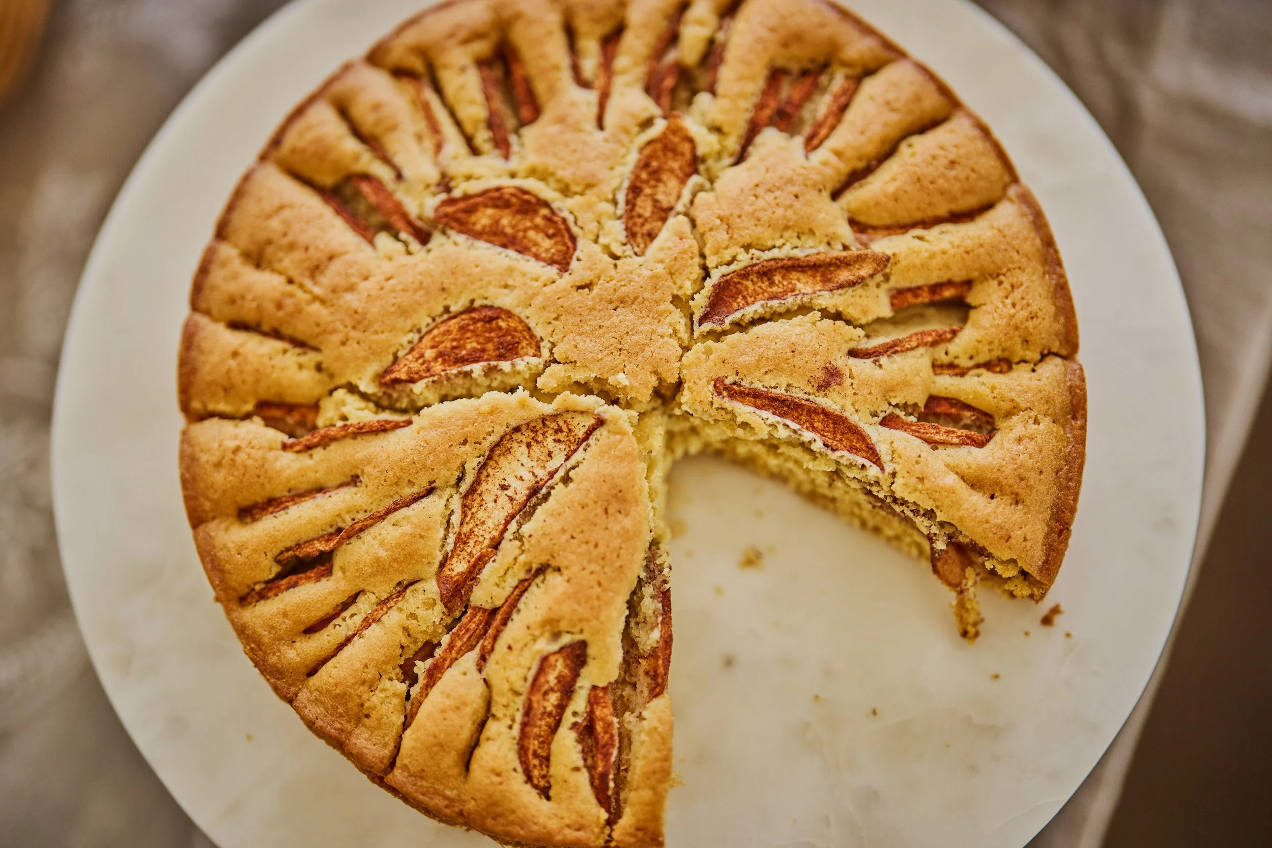 An apple cake with slices of apples on top, one slice removed.