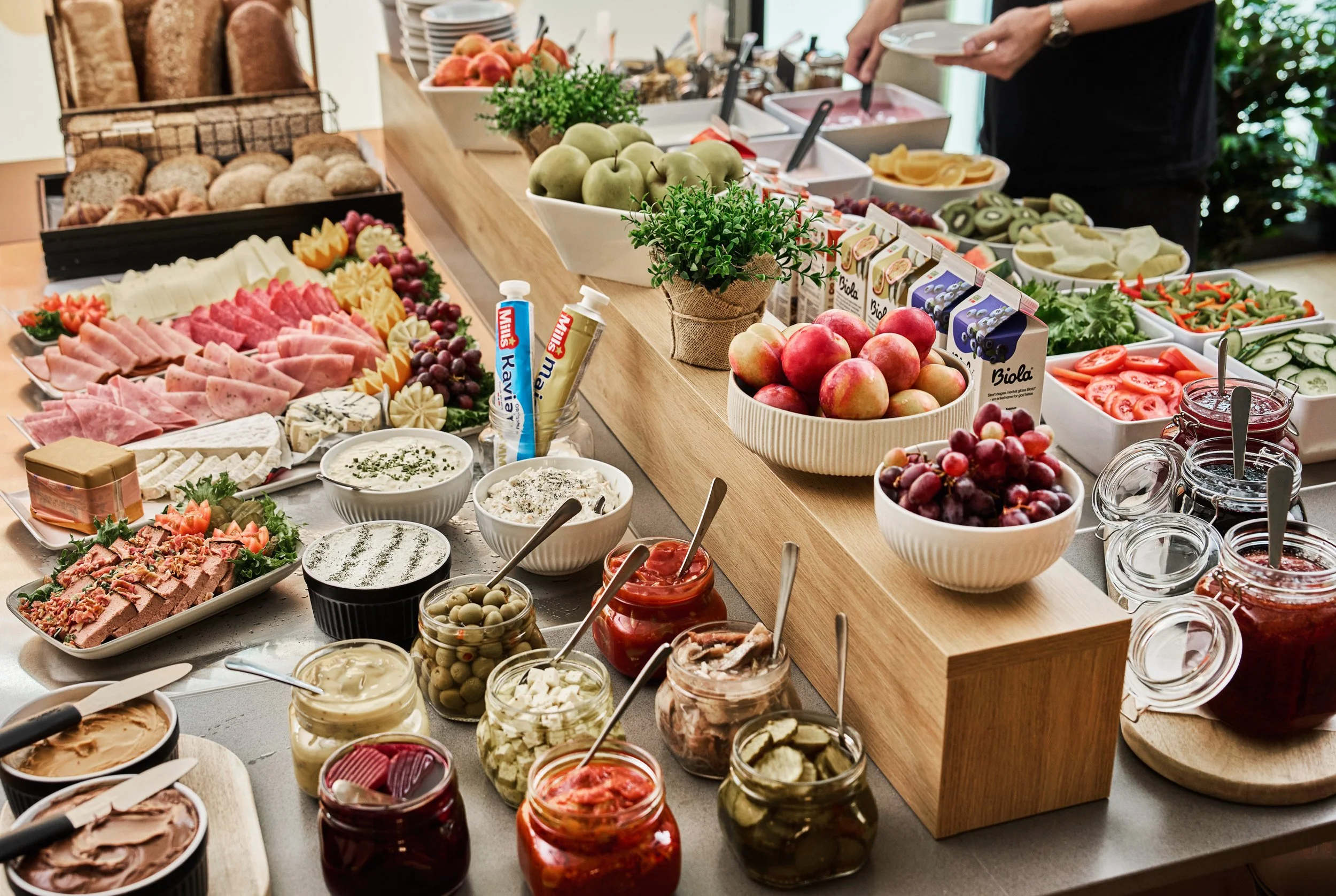 A buffet table with various fresh fruits, vegetables, cheeses, meats, and condiments.