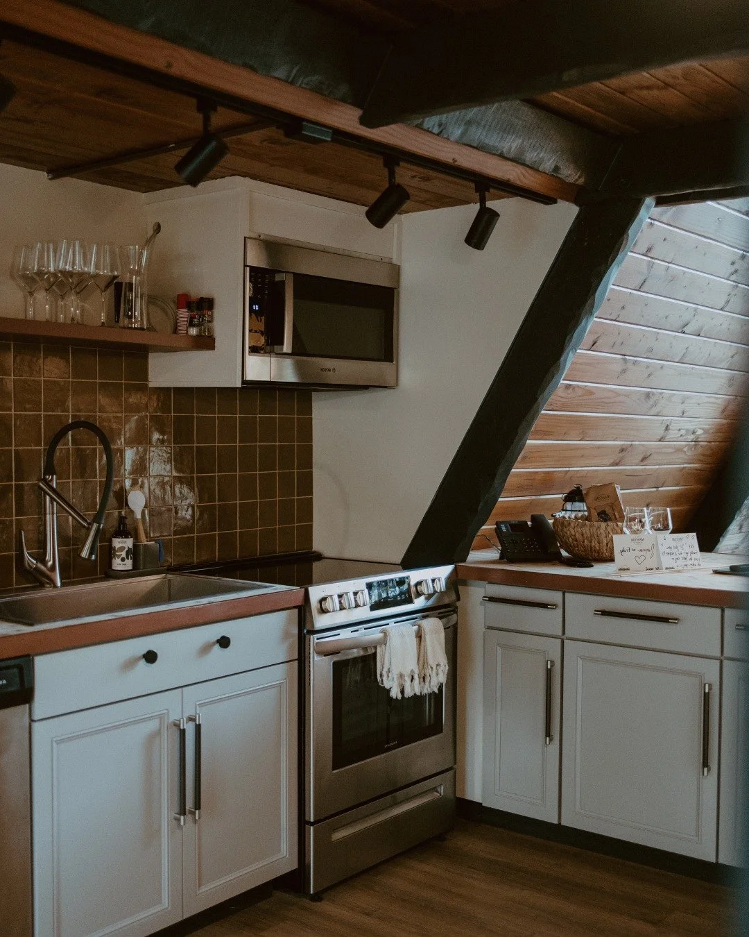 Travel Log | Gathered Here 

At the heart of the A-Frame, light pours through tall windows, warming wide-plank floors and cedar walls. The kitchen is clean-lined and quiet, ready for slow mornings or shared meals. 

A wide table nearby makes space fo