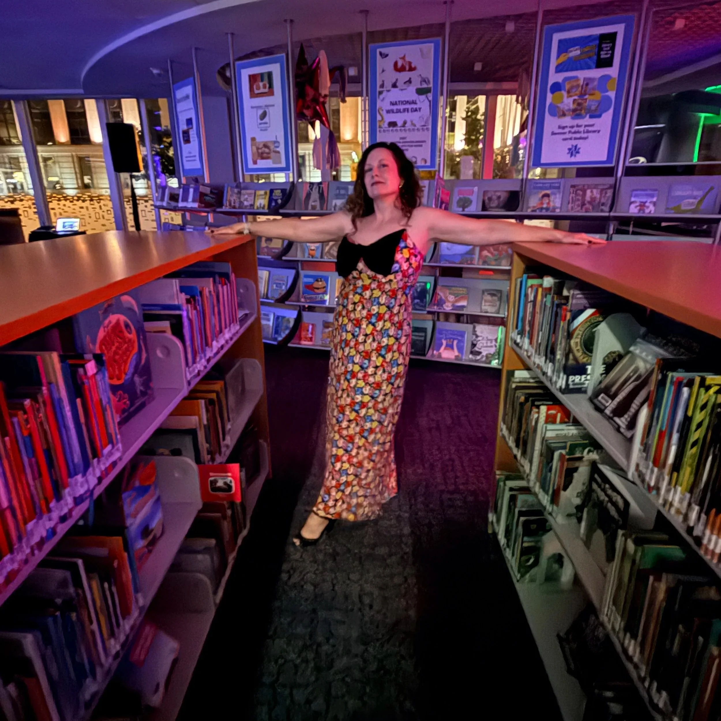Alison, in a colorful dress between two book shelves