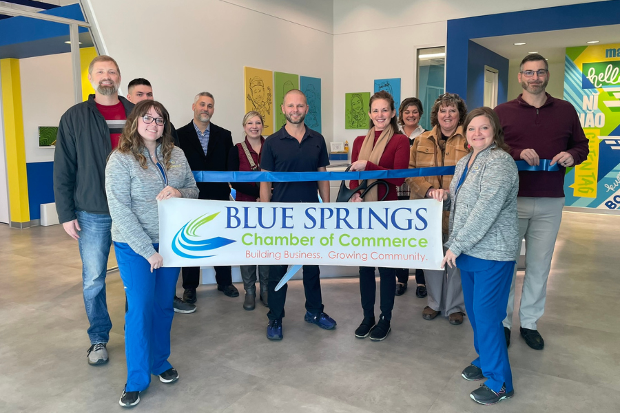 Group photo of people holding a banner and ribbon for a ribbon cutting