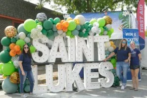 People posing in front of a balloon arch at a festival