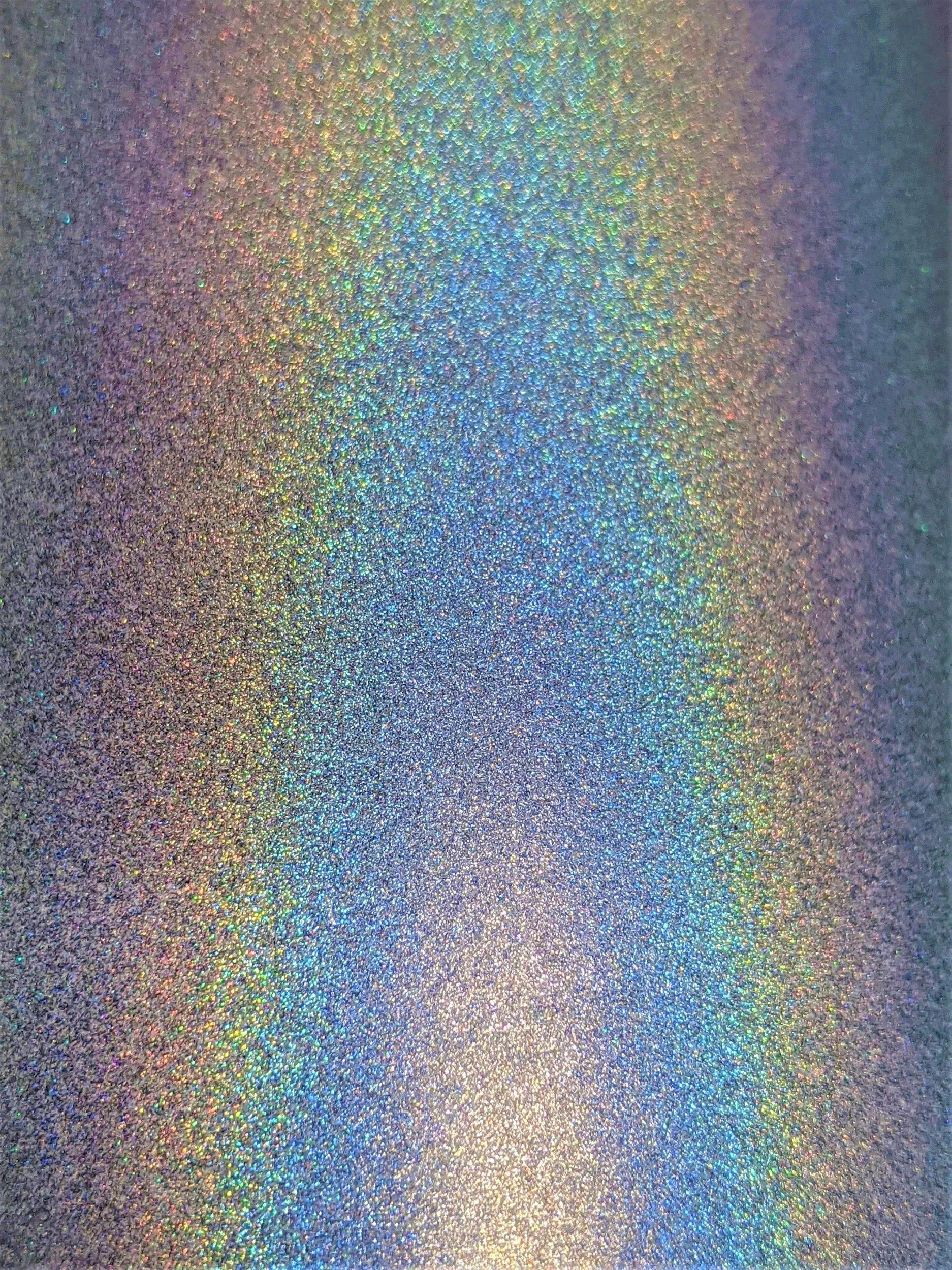 Close-up of a holographic, glittery surface reflecting multiple rainbow colors.