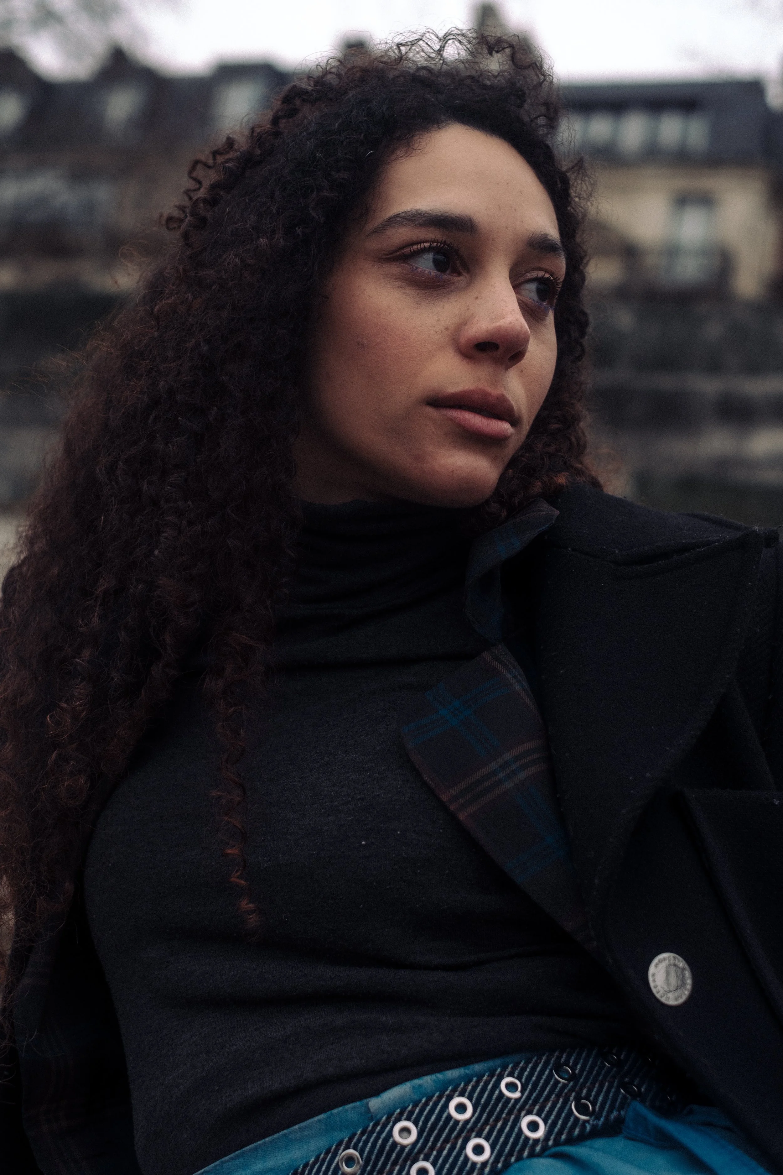 Photo shoot in Paris. Photography by Owen Clarke. Photo is of a woman taking in Paris. Sitting wearing a coat, top and blue skirt.