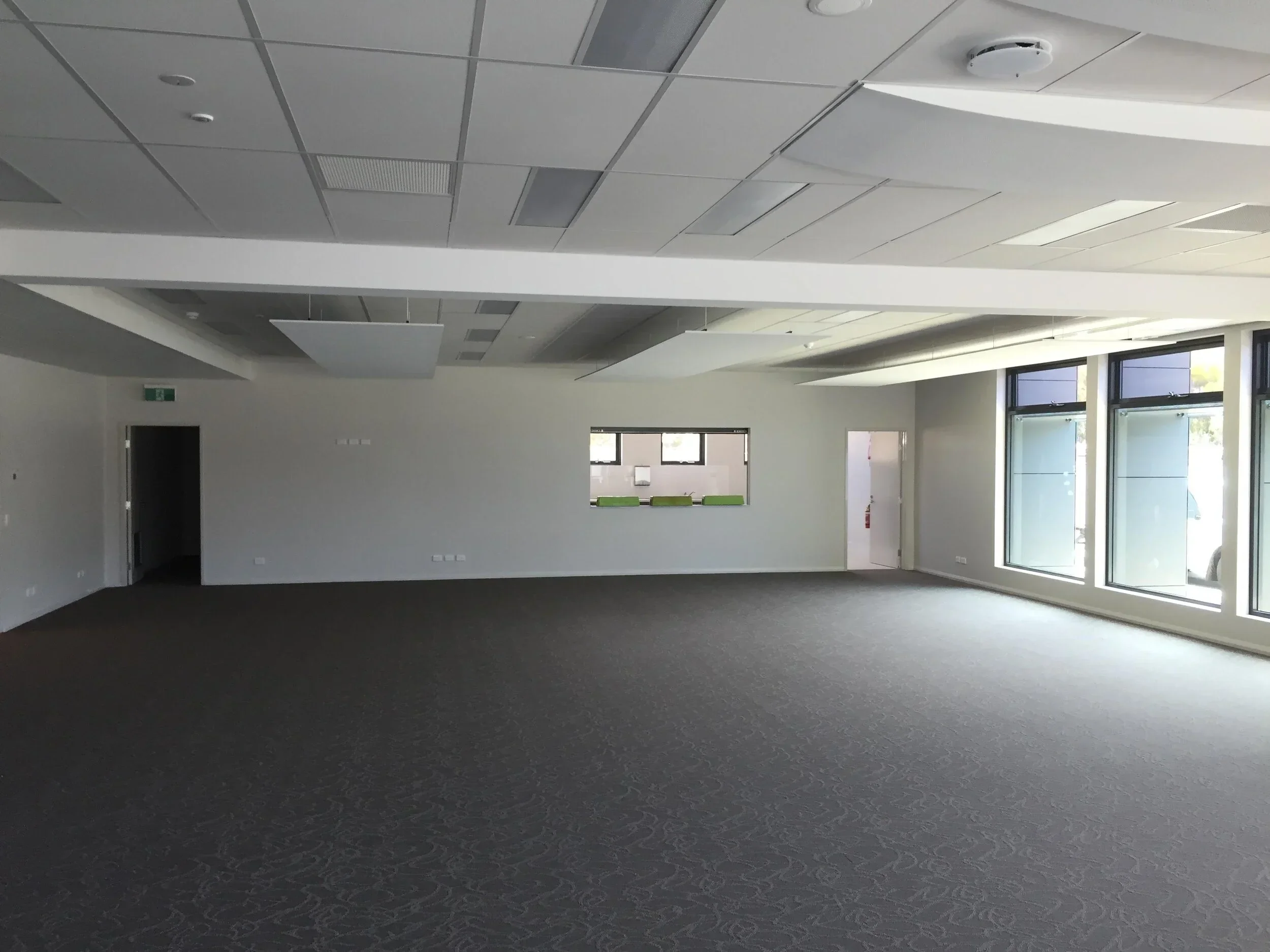 Large open-plan commercial interior in Perth with freshly painted white walls, professional acoustic ceiling tiles, and grey carpeting.