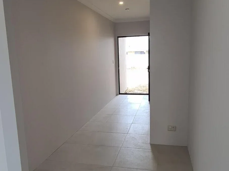 Long residential hallway in Perth with freshly painted neutral walls and light grey large-format floor tiles.