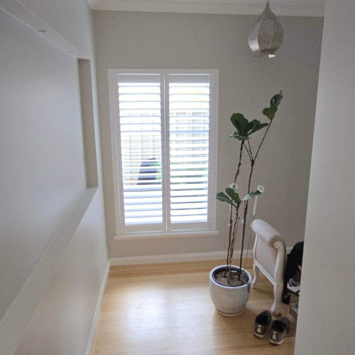 Bright entry foyer in a Salter Point home featuring neutral painted walls, plantation window shutters, and light timber floors.