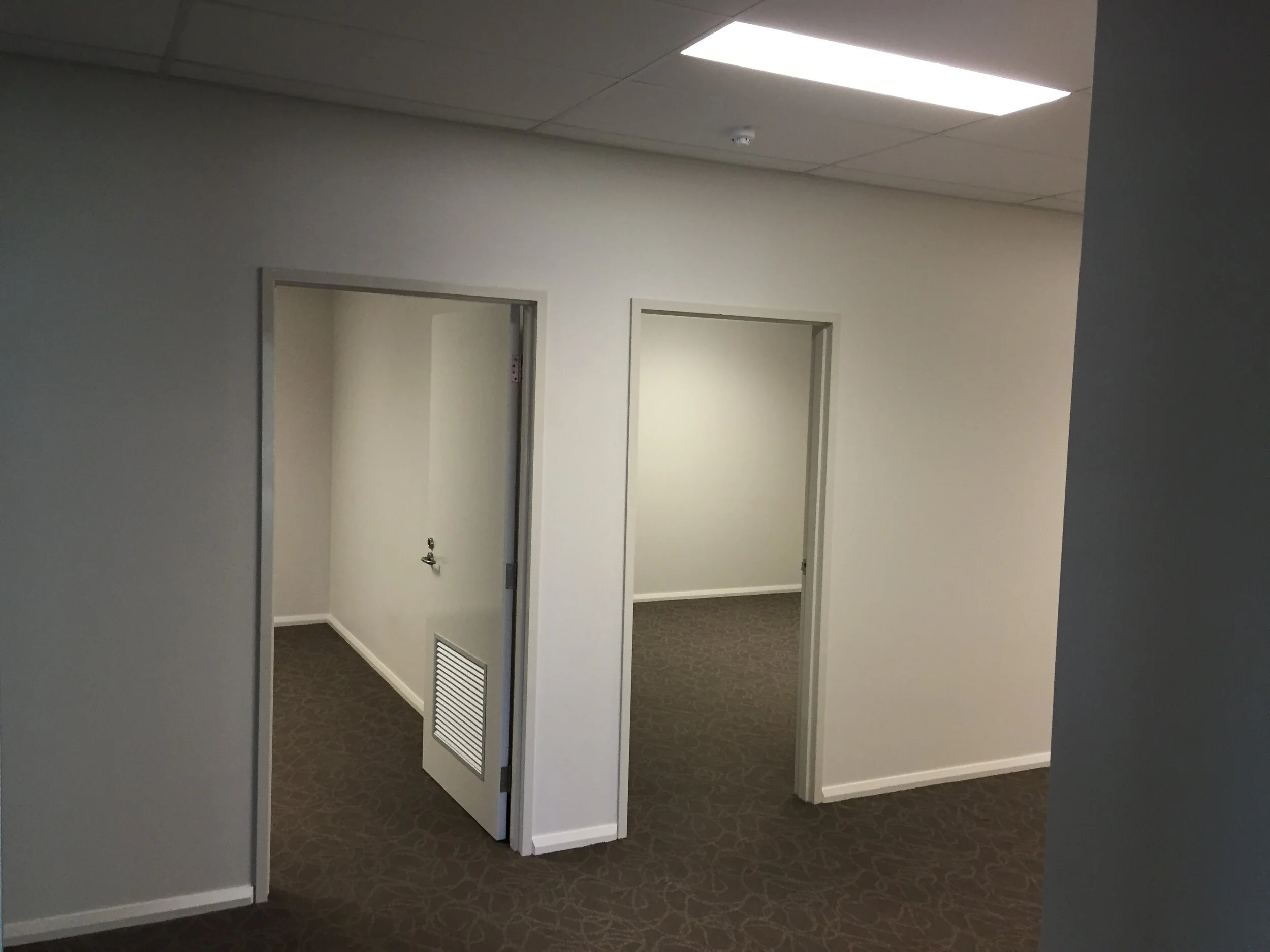 Professional interior painting in Cardup showing two open doorways, grey-toned walls, and commercial grey carpeting.