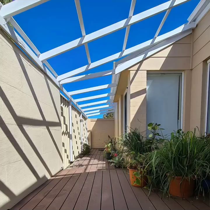 Side timber deck walkway featuring a white painted overhead timber pergola framework against beige cladding.