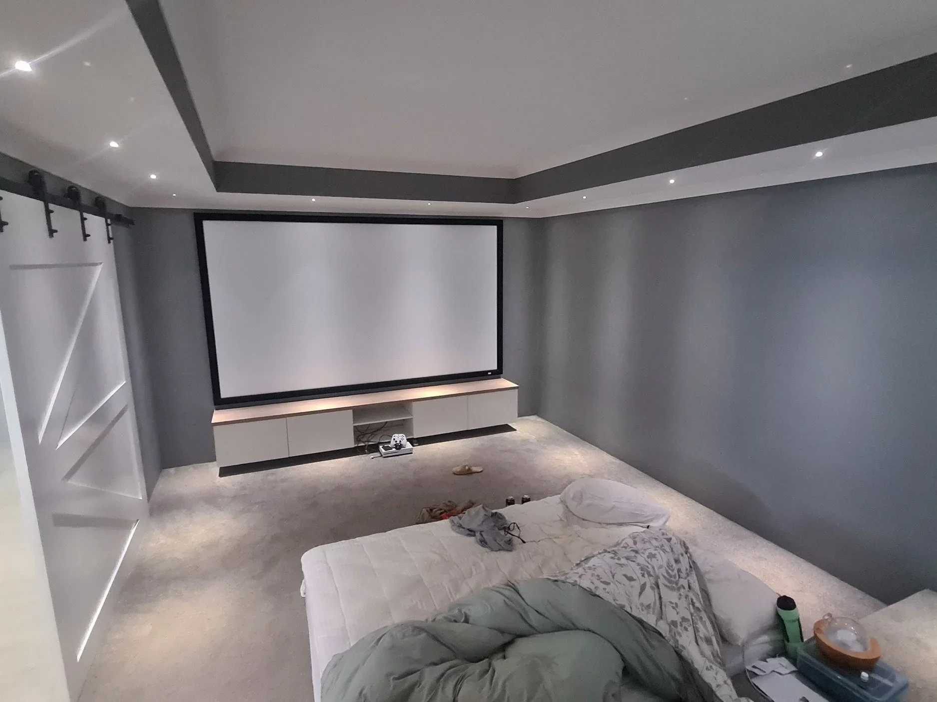 Modern home theater interior painted by Perth painters featuring dark grey accent walls and a crisp white ceiling.