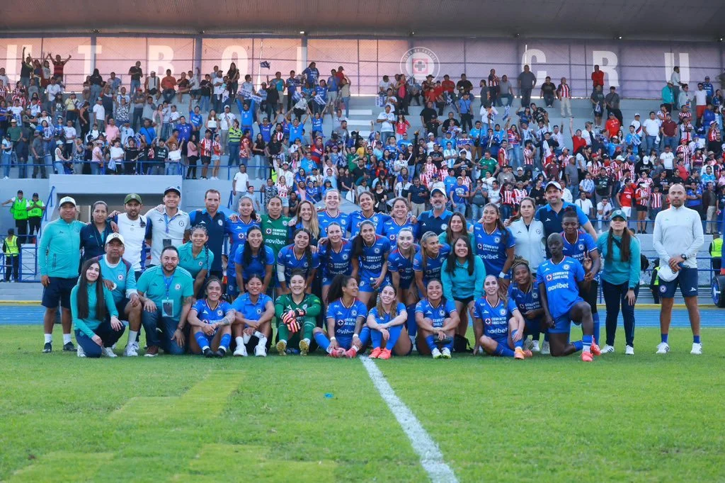 Jugadoras de Cruz Azul posan frente a la cámara con la afición de fondo