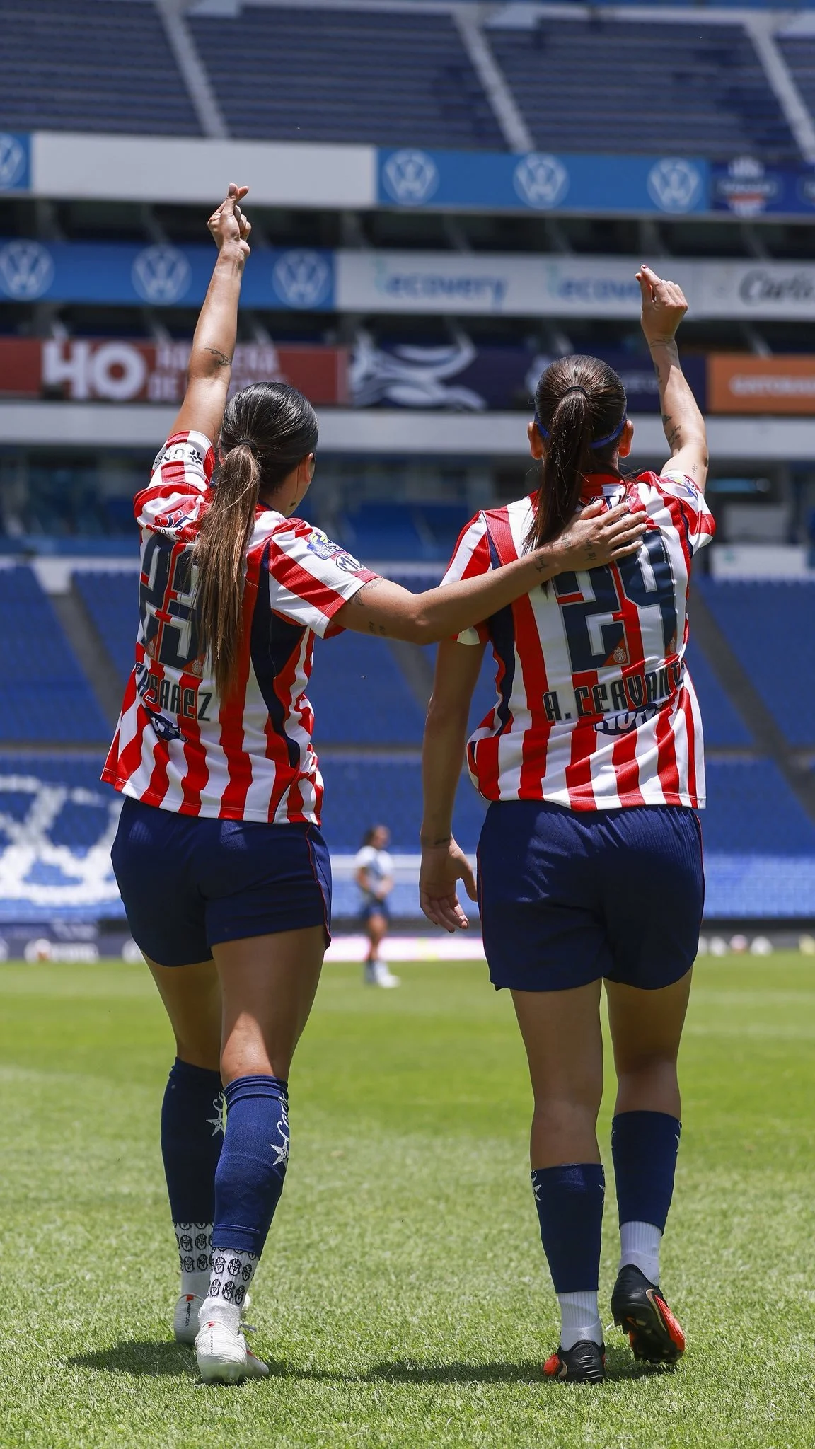 Jasmine Casarez y Licha Cervantes de espaldas alzando las manos haciendo un corazón coreano.